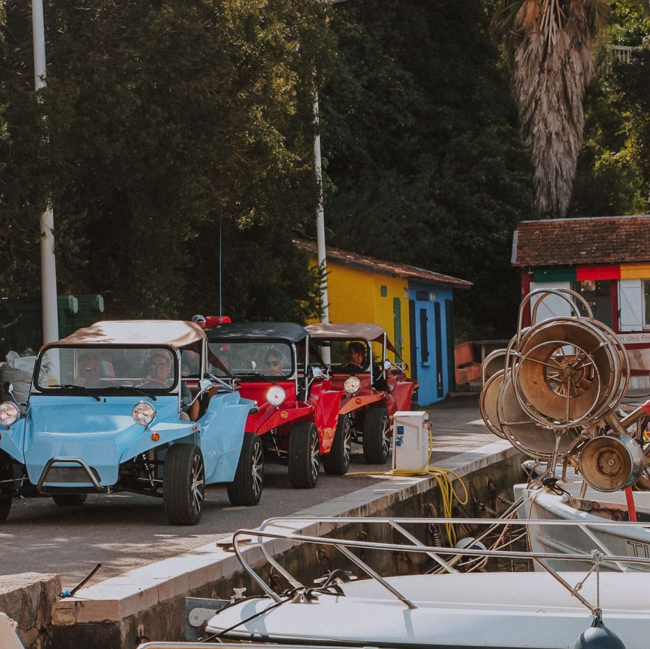 Buggys vintage bleu et rouges garés au bord d’un petit port, pendant une balade au départ de Cannes