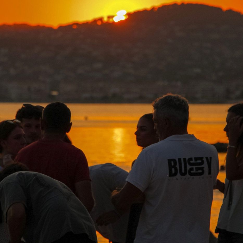 Groupe face au coucher du soleil sur la mer lors d’une balade en buggy vintage