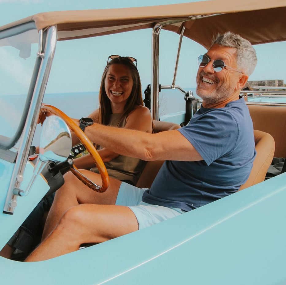 Duo souriant à bord d’un buggy vintage bleu ciel au départ de Cannes